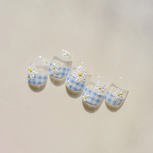 Detailed view of blue and white checkered press-on nails with 3D daisy flower accents