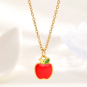 Detailed close-up of a red apple pendant necklace with gold chain and green leaf detail