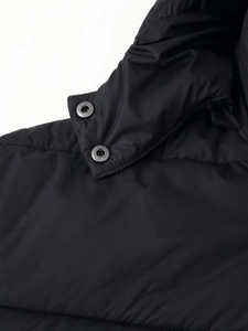 Detailed macro view of black quilted puffer jacket collar with metal snap buttons