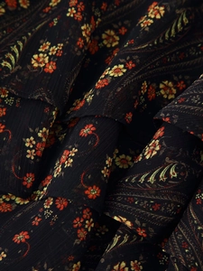 Detail of floral chiffon fabric with layered ruffles and intricate paisley patterns
