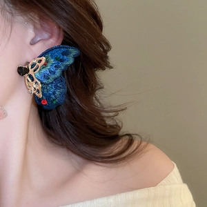 Detail of embroidered blue butterfly earring with colorful crystals on model's ear