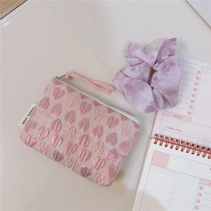 Detailed close-up of pink heart embroidery texture and woven simple wish label on pouch