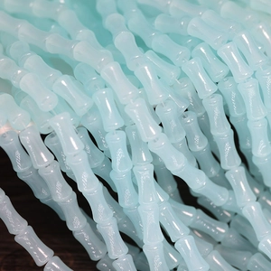 Macro shot of light blue glass bone-shaped beads with smooth semi-transparent finish