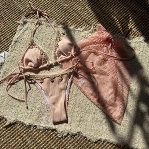 Close-up of pink three-piece bikini set with starfish charms and mesh sarong skirt