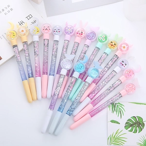 Colorful liquid glitter pens with cute cartoon toppers scattered on a white table