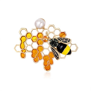 Macro shot of bee brooch with yellow enamel honeycomb and a white pearl accent