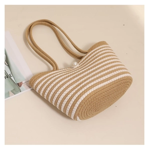 Detail of woven straw tote bag featuring white stripes and a decorative pearl button closure