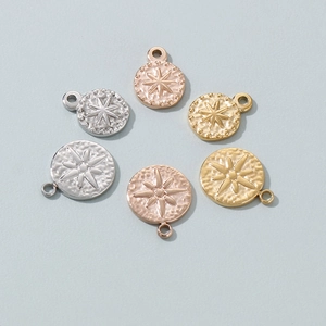 Detailed view of textured round metal charms with starburst pattern in gold and silver