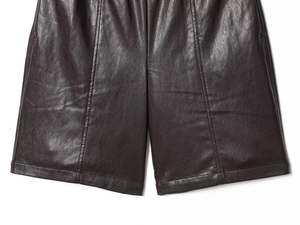 Detailed close-up of stitching and smooth texture on black faux leather shorts