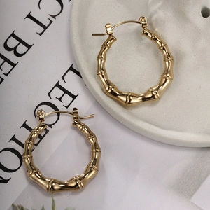 Detailed view of golden bamboo textured hoop earrings on a decorative white dish