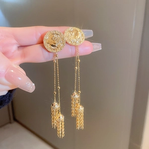 Close-up of gold lion head coin studs with long metal tassels and fringe detail