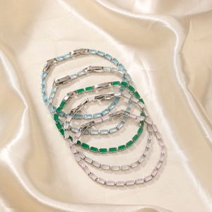 Colorful rectangular glass bead bracelets displayed on elegant light gold silk fabric