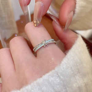 Detail of silver floral ring with blue enamel and cross star crystals on finger
