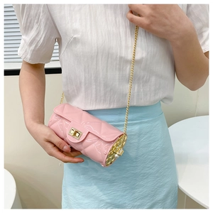 Close-up of pink quilted cylinder bag with gold chain strap and metallic lock detail