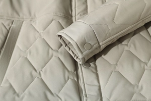 Detailed view of geometric quilting and matching button on a khaki winter coat for men