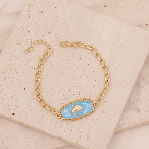 Macro detail of gold-plated Taurus zodiac chain bracelet with blue enamel inlay