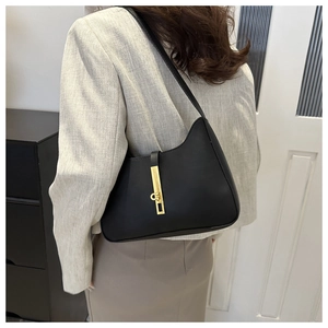 Detail of minimalist black leather half-moon shoulder bag with golden buckle on a model