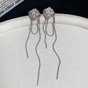 Detailed macro view of silver floral stud earrings with cascading metal fringe tassels