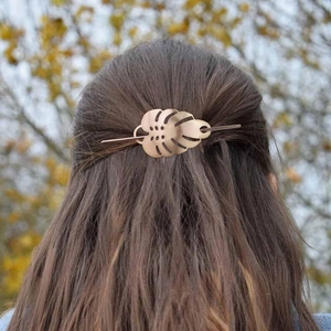 Close-up of a golden metal leaf hair pin styled on a woman's brown hair in natural light
