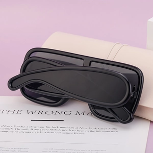 Detail of black oversized one-piece sunglasses placed on a minimalist beige case