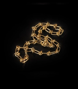 Close-up of a 18K gold-plated knotted thorn chain necklace over a black background