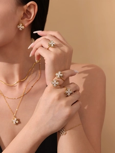 Detail showing gold four-leaf flower jewelry set with sparkling zircon on a model