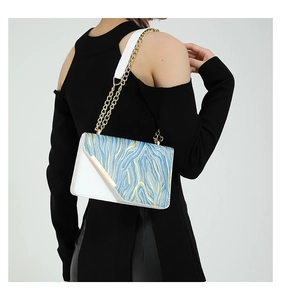 Detail of color-block shoulder bag with gold chain and blue textured leather flap