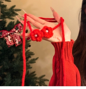 Close-up of handmade red crochet flower necklace with pearls on a festive background