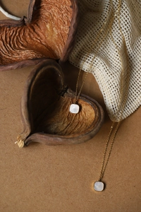 Macro detail of gold-plated square pendants with sunburst texture on a necklace
