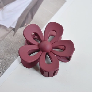 Close-up of a matte burgundy flower hair claw clip on a minimalist white background