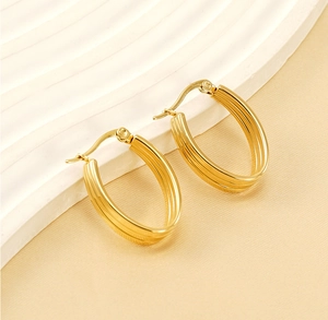Macro detail of triple-layered ribbed gold hoop earrings in polished stainless steel