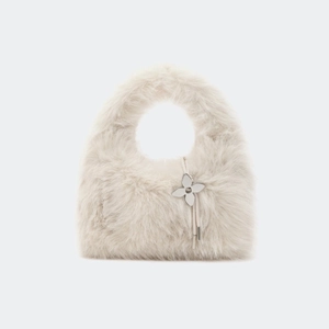 Détail du sac à main en fausse fourrure douce avec un pendentif trèfle en métal argenté