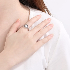 Minimalistischer Edelstahlring in Silber mit weißer Perle an einer Frauenhand