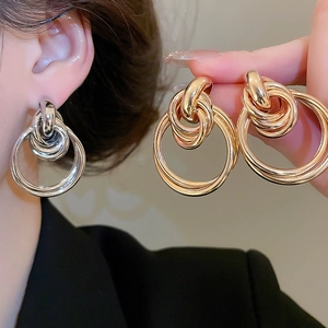 Detail of layered gold and silver multi-hoop earrings showing polished texture