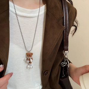 Close-up of brown flocked bear necklace with silver star and pearls on a model