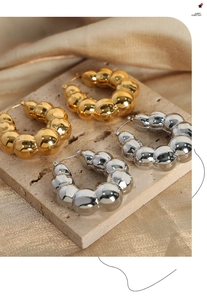 Detailed view of thick bubble hoop earrings in gold and silver on marble stone