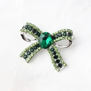 Elegant bow brooch with green rhinestones and emerald-colored crystal for suit accessory