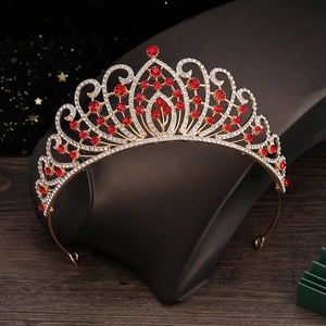 Macro shot of gold wedding tiara featuring red rhinestones and sparkling crystal accents