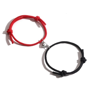 Detail of adjustable couple bracelets with magnetic heart charm on white background