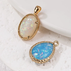 Gold-plated opal charms in white oval and blue teardrop shapes on white stone