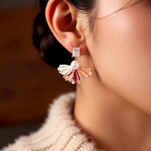 Détail de boucles d'oreilles pétales vintage avec zircon et perle sur mannequin en pull