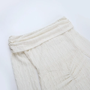 Détail de la robe de soirée blanc cassé montrant la texture gaufrée et l'encolure bateau