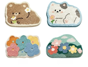 Detail view of four plush bathroom mats featuring bear, cat, and floral cartoon patterns
