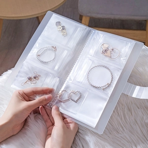 Transparentes Schmuckaufbewahrungsalbum für Ohrringe und Armbänder auf einer weichen Decke