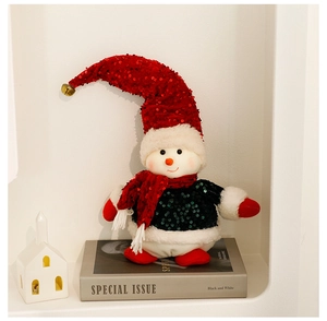 Detail shot of a plush Christmas snowman doll with red and green sequins on a display shelf