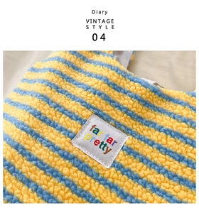 Detailed close-up of striped plush fabric texture and colorful brand label on tote bag