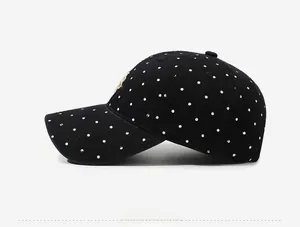 Side view of black washed cotton baseball cap with white polka dots and gold embroidery