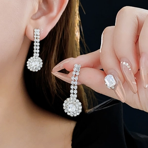 Detail of silver drop earrings with sparkling heart and star zirconias worn by model