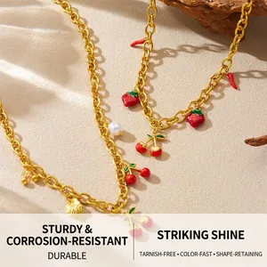 Detail of gold chain necklace featuring strawberry and cherry enamel pendants with pearls