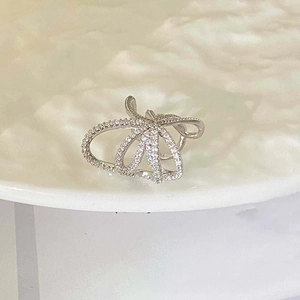 Minimalist multi-layer zircon bow ear cuff in silver finish displayed on a white plate